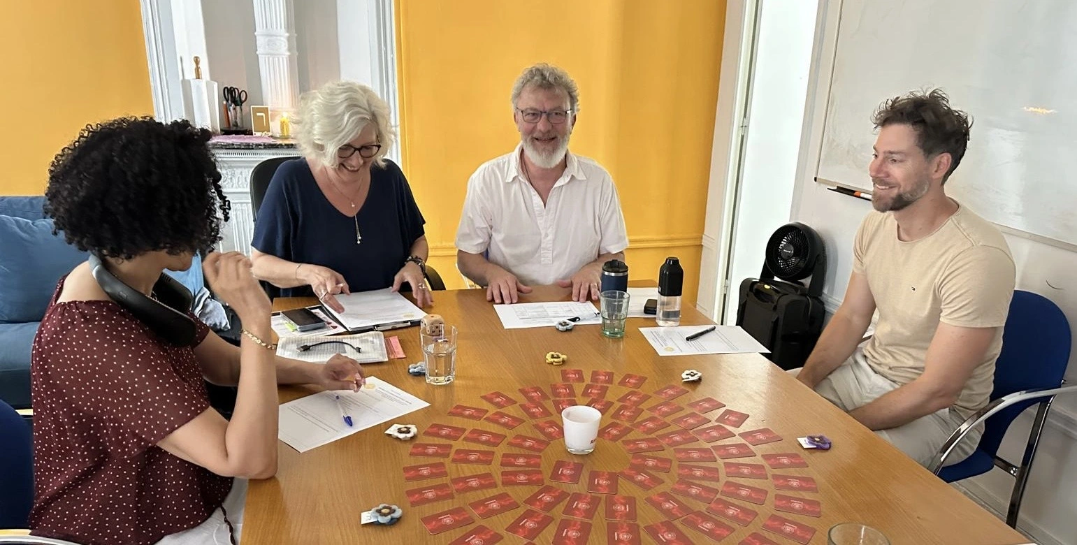 Quatre participants souriants expérimentent Cap Agapé autour d’un mandala de cartes